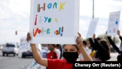 Seorang siswa memajang spanduk yang mendorong pengendara untuk memberikan suara pada sore hari pemilihan presiden di South Tucson, Arizona, AS, 3 November 2020. (Foto: REUTERS/Cheney Orr)