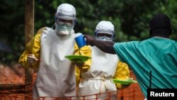 FILE - Medical staff working with Medecins Sans Frontieres (Doctors Without Borders) prepare to take food to patients in the isolation area of an Ebola treatment center in Sierra Leone's Kailahun district, July 20, 2014.