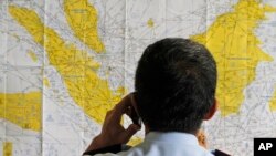 Seorang petugas bandara tengah mengamati peta Indonesia di bandara Juanda, Surabaya (Foto: dok). Pesawat milik Aviastar MV 7503 dari Masamba menuju Makassar dilaporakan hilang kontak, Jumat (2/10) setelah terbang selama 11 menit.