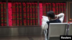 一位股民在股价电子屏幕前看报纸