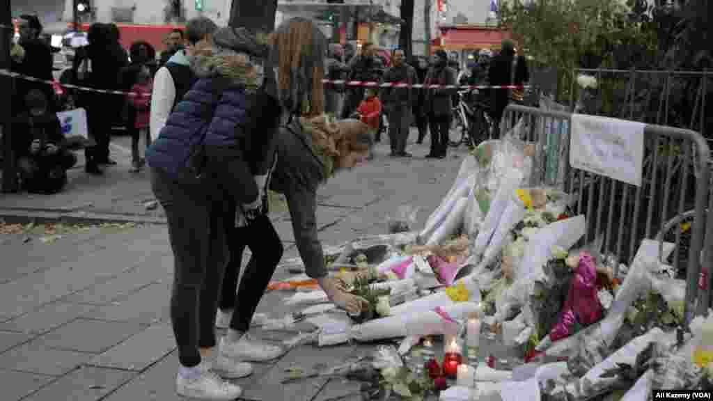 People lay flowers as part of a memorial to victims a day after more than 120 people were killed in a series of attacks in Paris, Nov. 14, 2015.