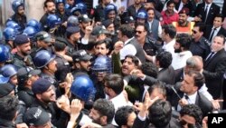 Pakistani police officers try to stop protesters from reaching the Line of Control between Pakistan and Indian Kashmir, at the border town of Chakoti, in Pakistani Kashmir, Thursday, Aug. 29, 2019.