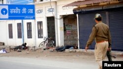 A policeman walks past injured tribal demonstrators after a clash during a protest at Dekiajuli town in the northeastern Indian state of Assam, December 24, 2014.