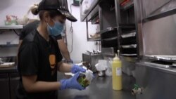 Finance manager Cassandra Poon now spends a couple days of a week taking orders at the register and assembling burgers at the counter instead of just sitting behind her desk. (Dave Grunebaum/VOA)