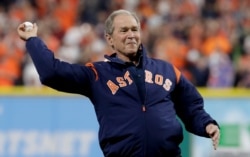 FILE- Former President George W. Bush throws the ceremonial first pitch before Game 5 of baseball's World Series between the Houston Astros and the Los Angeles Dodgers, in Houston, Oct. 29, 2017.