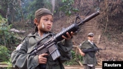 Dalam foto dokumentasi yang diambil tahun 2000 ini, nampak Samboo, seorang bocah berusia 12 tahun tengah berpose dengan senapan miliknya di sebuah hutan dekat perbatasan Thailand. Samboo, salah satu dari tentara anak yang direkrut untuk memperkuat barisan pemberontak Karen untuk melawan pemerintahan militer Burma. (File: dok).