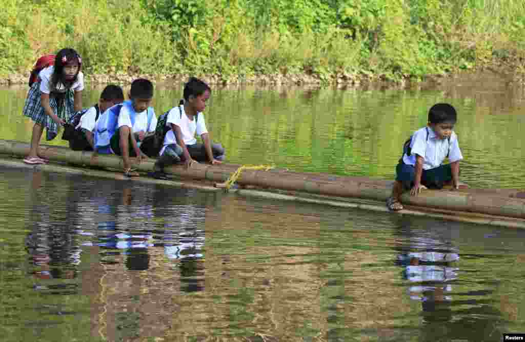 Anak-anak SD di kota Rodriguez, provinsi Rizal, Filipina menyeberangi sungai dengan rakit saat pergi sekolah.