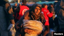 一名从反政府武装控制的阿勒颇东城区转移出来的平民抱着大饼和其他人一道抵达叙利亚反政府武装控制的拉西迪恩镇。（2016年12月15日）