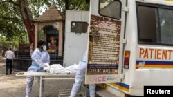 Health workers carry the body of a person, who died from complications related to the COVID-19, for cremation at a crematorium in New Delhi, India, June 10, 2021.