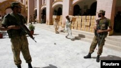 Pakistani soldiers stand guard outside a district court as election commission workers carry election materials in Hyderabad, May 8, 2013.