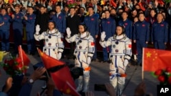 Chinese astronauts for the Shenzhou-17 mission, from left, Jiang Xinlin, Tang Hongbo and Tang Shengjie wave as they attend a send-off ceremony for their manned space mission at the Jiuquan Satellite Launch Center in northwestern China on October 26, 2023. (AP Photo/Andy Wong)