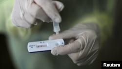 FILE - A health care worker holds a rapid COVID-19 antigen test at a coronavirus testing center in Nice, France, Oct. 15, 2020. Millions of such kits are heading to Africa for distribution.