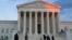 People stand on the plaza in front of the Supreme Court at sunset, Feb. 13, 2016, in Washington. 