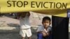 A Cambodian girl holds a banner next to a boy as former residents of the Dey Krahorm community gather in front of the site where they used to live before being evicted by government forces in Phnom Penh January 24, 2012. 