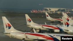 FILE - Ground crew work among Malaysia Airlines planes on the runway at Kuala Lumpur International Airport (KLIA). 