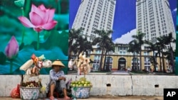 រូបឯកសារ៖ អ្នក​លក់​ផ្លែឈើ​​អង្គុយ​លក់​ផ្លែឈើ​តាម​ដង​ផ្លូវ​ក្បែរ​ផ្ទាំង​ផ្សាយ​ពាណិជ្ជកម្ម​​មជ្ឈមណ្ឌល​ពាណិជ្ជកម្ម​មួយ​ក្នុង​ទីក្រុង​ហូរជីមិញ ប្រទេស​វៀតណាម ថ្ងៃទី ២៩ ខែមេសា ឆ្នាំ​២០១៥។ 