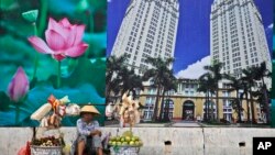 រូបឯកសារ៖ អ្នកលក់ដូរម្នាក់អង្គុយនៅផ្ទាំងបដាផ្សាយ ពាណិជ្ជកម្មពីផ្សារទំនើបមួយ នៅក្រុងហូជីមិញ ប្រទេសវៀតណាម កាលពីថ្ងៃទី២៩ ខែមេសា ឆ្នាំ២០១៥។