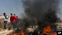 Demonstran Palestina membakar ban dan bentrok dengan tentara Israel setelah tentara Israel menggeledah rumah Omar al-Abed, 20, yang diidentifikasi oleh tentara Israel sebagai pelaku penyerangan di pemukiman Israel, Halamish.