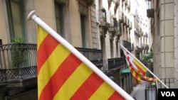 Warga Barcelona pendukung otonomi Catalonia ikut mengibarkan bendera Catalonia.