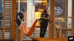 Police officers carry a body bag from a bus stop where a suspected suicide bombing occurred in Jakarta, Indonesia, May 25, 2017.