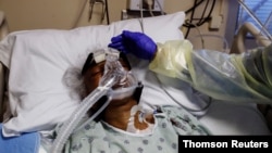 Medicinska sestra Alma Abad dodiruje glavu pacijenta obolelog od koronavirusa, na odeljenju Intenzivne nege u bolnici Ruzland, u južnom delu Čikaga