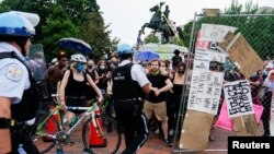 Petugas Polisi Taman AS bentrok dengan para pengunjuk rasa yang melindungi demonstran lain yang mencoba merobohkan patung Presiden AS Andrew Jackson di tengah-tengah Taman Lafayette di depan Gedung Putih, Washington, DC, 22 Juni 2020. 