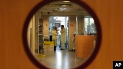 FILE - Doctors visit a patient at the intensive care unit of a children's hospital in Brussels, Nov. 25, 2013. 