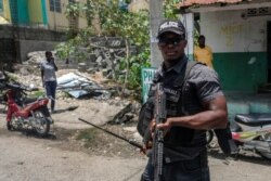 Police stand guard near the entrance of a Red Cross center after people entered and took off with several foam mattresses, in Les Cayes, Haiti, Aug. 20, 2021, six days after a 7.2 magnitude earthquake hit the area.