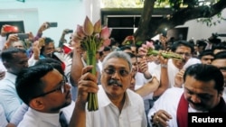 Gotabhaya Rajapaksa (C), former defense secretary and brother of Sri Lanka's ex-president Mahinda Rajapaksa, holds the symbol of the Sri Lanka People's Front, at a party event in Colombo, Sri Lanka, July 4, 2018.