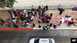 FILE - Migrants gather to hear names called from a waiting list to claim asylum in the U.S., at the U.S.-Mexico border in Tijuana, Mexico, Nov. 10, 2019.