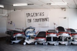 FILE - A picture taken on April 3, 2020 shows a banner reading "Emergency services are suffering" above empty stretchers in the hall of the emergency services of the Aix Hospital Center in Aix-en-Provence, southern France.