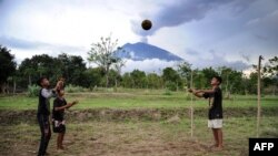 Anak-anak bermain bola dengan pemandangan Gunung Agung di Karangasem, Bali, 30 November 2017.