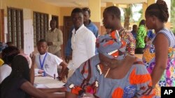 Une femme met son bulletin dans l'urne au bureau de vote de Seme Podji, au Bénin, le 6 mars 2016. (AP Photo/Virgile Ahissou)