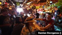 In this Wednesday, July 7, 2021, file photo, patrons enjoy cold tropical cocktails in the tiny interior of the Tiki-Ti bar as it reopens on Sunset Boulevard in Los Angeles.(AP Photo/Damian Dovarganes, File)