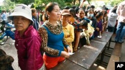 Cambodian villagers line up to cast their vote in the country's national election at a polling station at Chak Angre Leu pagoda, in Phnom Penh, Cambodia, Sunday, July 28, 2013. 