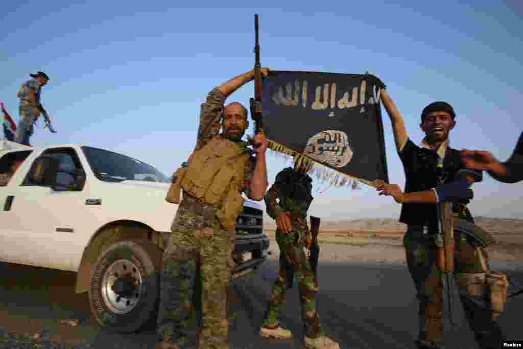 Iraqi Shiite militia fighters hold the Islamic State flag as they celebrate after breaking the siege of Amerli by Islamic State militants, Sept. 1, 2014. 