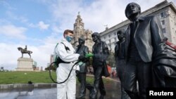A worker disinfects a statue of the Beatles amid the coronavirus pandemic, in Liverpool, Britain, Oct. 1, 2020.