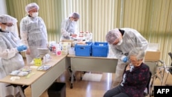Seorang perempuan lansia menerima dosis pertama vaksinasi COVID-19 di distrik Setagaya, Tokyo, 12 April 2021 saat Jepang mulai memvaksinasi para lansia. (Foto: STR / berbagai sumber / AFP)