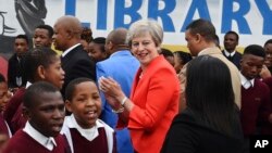 La première ministre britannique Theresa May rencontre des élèves lors d'une visite au lycée ID Mkhize à Gugulethu, au Cap, en Afrique du Sud, le 28 août 2018.