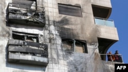 Two men stand on the balcony of a buildling reportedly targeted by Israeli air strikes in the Syrian capital Damascus on Feb. 21, 2024.