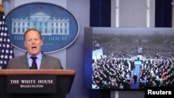 Press Secretary Sean Spicer delivers a statement while television screen show a picture of U.S. President Donald Trump's inauguration at the press briefing room of the White House in Washington, Jan. 21, 2017. 