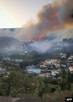 Foto ini menunjukkan kebakaran hutan yang mengamuk di dekat bangunan di Pulau Canary La Palma, pada 16 Juli 2023.(AFP)