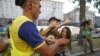A protester from Ukrainian women rights group Femen is carried away by security guards during a protest in Kyiv against prostitution, June 19, 2012.