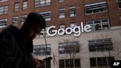 FILE - A man using a mobile phone walks past Google offices in New York, Dec. 17, 2018.
