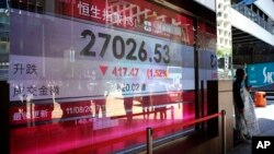 A man walks past an electronic board displaying the Hong Kong share index outside a local bank in Hong Kong, Aug. 11, 2017. 