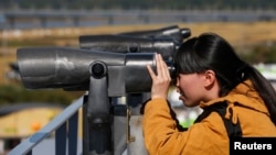 FILE - A Chinese tourist looks towards the north through a pair of binoculars at the Imjingak pavilion near the demilitarized zone which separates the two Koreas, in Paju, north of Seoul, Oct. 16, 2013. 