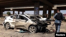 A member of the Iraqi security force inspects the site of a car bomb attack in Ramadi, April 16, 2014.