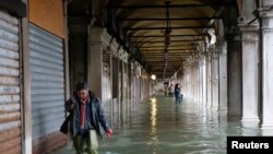 A person walks in the flooded St. Mark's Square during a period of seasonal high water in Venice, Italy, Nov. 12, 2019.