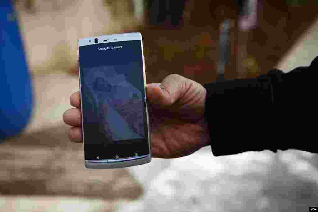 A Syrian shows a picture of himself in a Syrian government hospital where he says he was chained to the bed because he was accused of being a terrorist. (Y. Weeks/VOA)