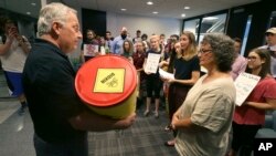 David Gray, left, director of external affairs at the Environmental Protection Agency Region VI office, accepts a barrel of letter from members of the Texas Campaign for the Environment at the EPA office in Dallas, Oct. 12, 2017. The letters to the EPA are calling for saving federal cleanup programs under the Trump Administration. The EPA has approved a plan to remove sediments laced with highly toxic dioxin from a partially submerged Superfund site near Houston damaged during Hurricane Harvey. 